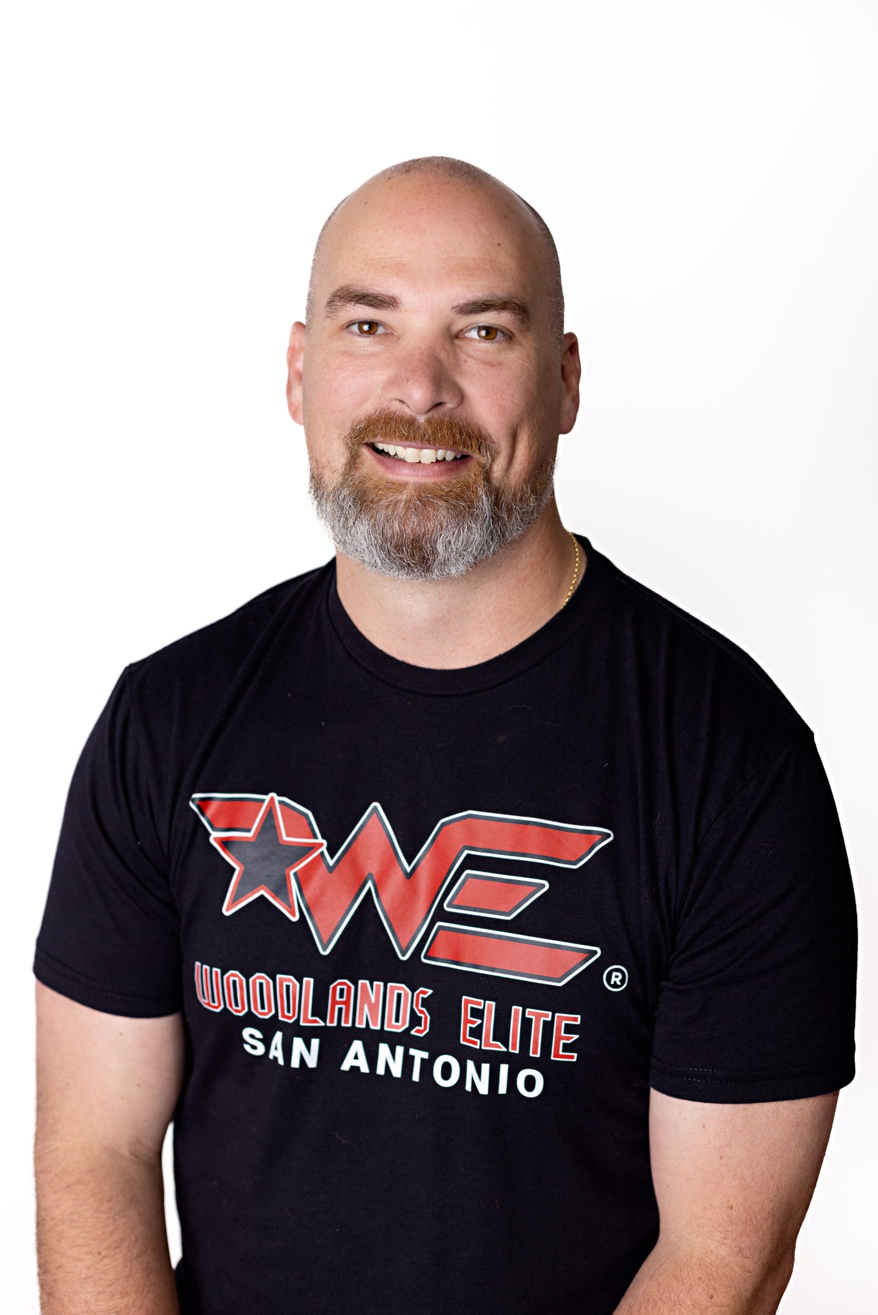 Smiling woman with long brown hair wearing a black T‑shirt with a large red WE graphic and white text, against a white background (San Antonio, TX design on shirt).
